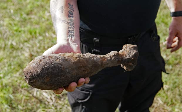 Per Olsen fandt lørdag en mortergranat med sin metaldetektor på marken mellem Tiphedevej og Kvie Søvej. En af bomberydderne viser granaten frem.