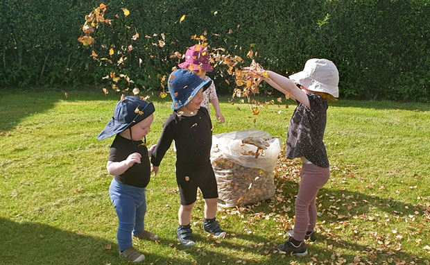 Børn fra Ansager dagpleje skaber et efterårsregn af birkeblade fra kirketræerne. Smil, latter og bare tæer dominerer i sanse-haven på denne dejlige sensommerdag